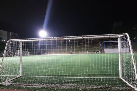 Night view of a soccer goal net under flood lights. Closeup view of goal net in a soccer playgroundの写真素材