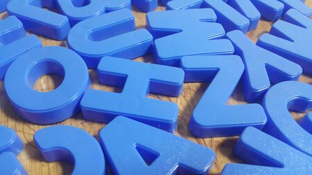 Set of plastic alphabet letters placed on a wooden floor. Alphabet set is used for educating...