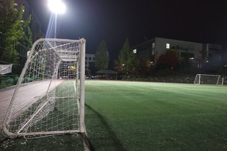 Night view of a soccer goal net under flood lights. Closeup view of goal net in a soccer playgroundの写真素材