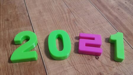 Plastic colored alphabets making words 2021 are placed on a wooden floor. These plastic letters can be used for teaching kids.の写真素材