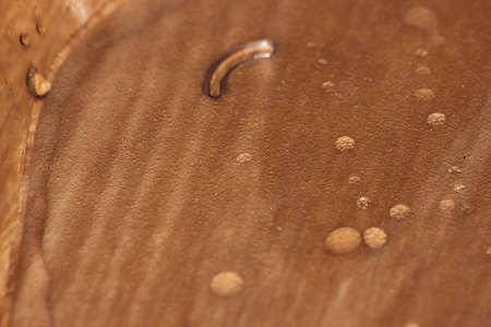Closeup selective focus view of water drops on wooden floor. Abstract raindrops pattern on wooden boardの写真素材