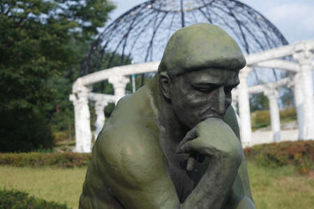 CHUNCHEON, SOUTH KOREA- JANUARY-10, 2019: Green statue of thinker Auguste Rodin, setting naked on a rock in a public parkのeditorial素材