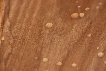 Closeup selective focus view of water drops on wooden floor. Abstract raindrops pattern on wooden...