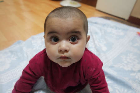 Baby girl with lovely face, big eyes and cute face gesture. Toddler baby making sweet activitiesの写真素材