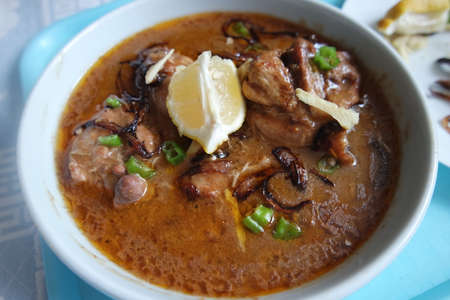 Closeup view of traditional Pakistani Haleem dish with salad and Lemon juice.