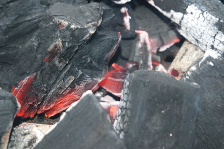 Fire on logs in fire pot with embers and burning coal. Bonfire with blazing red and orange fire flames. Fire background with woods and planks on fire at night view.の写真素材