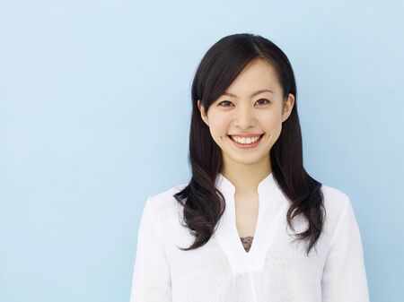 Happy young japanese girl isolated on blue backgroundの写真素材
