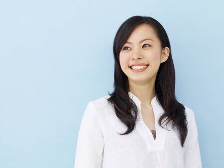 Happy young japanese girl isolated on blue backgroundの写真素材