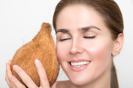 Gorgeous woman is smiling and holding a coconut in her handの写真素材