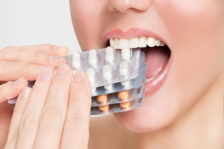 Beautiful woman's mouth bites on tablet packsの写真素材