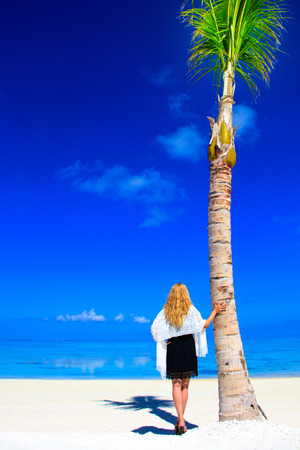 Blond woman with black dress on the sandy beachの写真素材