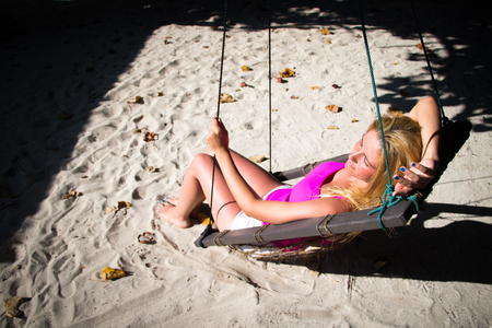 Gorgeous blond woman is rocking under the treeの写真素材