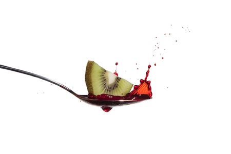 A Kiwi dropped onto a spoon filled with colored waterの写真素材