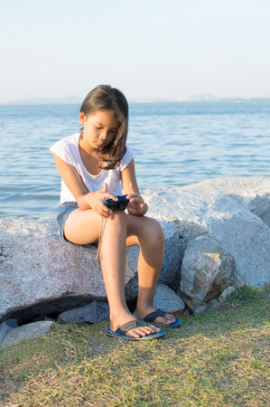 kid with digital photo camera on the sea side.の写真素材