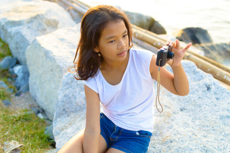 kid with digital photo camera at the side of the sea.の写真素材