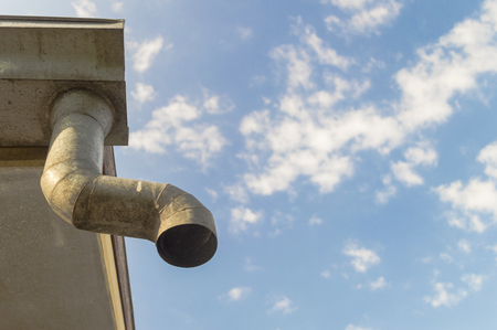 old zinc gutter under a cloudy sky on the old house.の写真素材