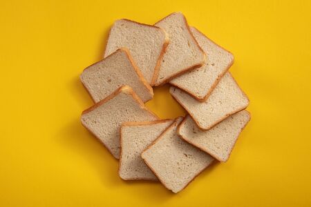 The bread on the table view from above in the form of a circle. Square white bread in square slices.
