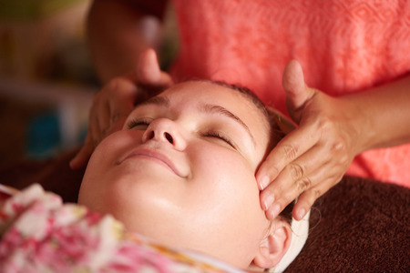 Young girl smiling while getting a massage during her facial from her local beautician.の写真素材
