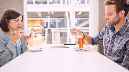 Woman pulls her face funny as she looks at her male partner while he removes his tea bag from his tea. She apperas to be irritated with his behaviour, evident from the status of their relationshipの写真素材