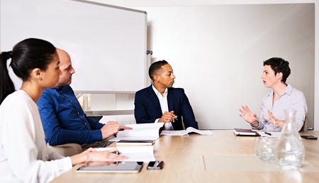 four young diverse business partners conducting a meeting in the board room of their new offices at...