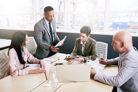 Professional business manager supervising a business meeting taking place between three of his...