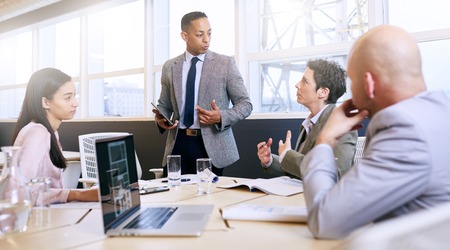 Professional mature adult mixed race well dressed businessman conducting a presentation in a bright...
