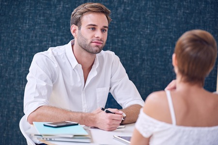 Man paying close attention to the woman he is having a meeting with as she explains the details of her business plan to him.の写真素材