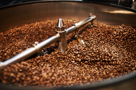Stainless steel arms mixing freshly roasted coffee beans in large stainless steel cooling drum where the beans are cooled down before packaging or storing them.の写真素材