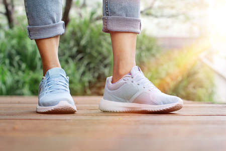 Woman in blue sneakers and blue jeans, on the wooden bridge by the water.の写真素材
