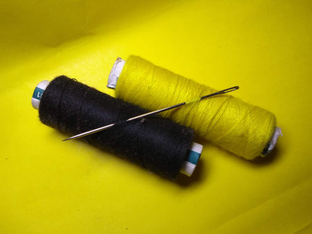 thread and needle on a yellow background. sewing accessories. close up