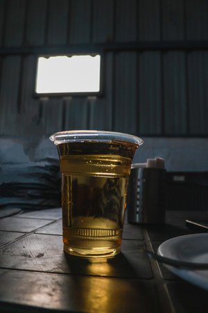 A cup of whiskey on a wooden table in a dark room.の写真素材