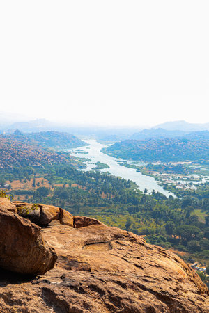 View from a hill in Karnataka frames a winding river and lush valley between rocky cliffs.の写真素材