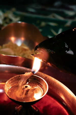 Sacred brass oil lamp with bright flame during Hindu prayer ritual in a temple setting.の写真素材