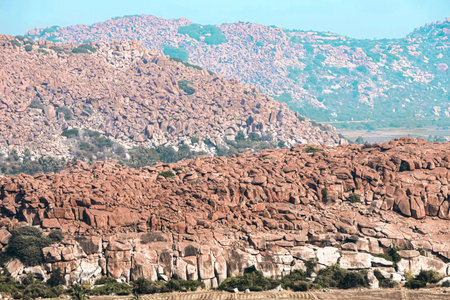 Elevated perspective of Anjanadri hill reveals boulders, vegetation, and distant mountains blending into a serene panorama.の写真素材