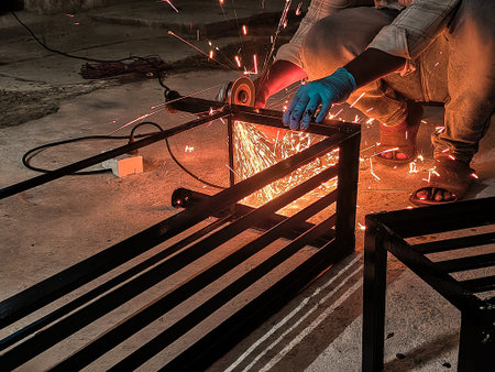 Worker cutting metal with arc welding machine at construction site, closeup