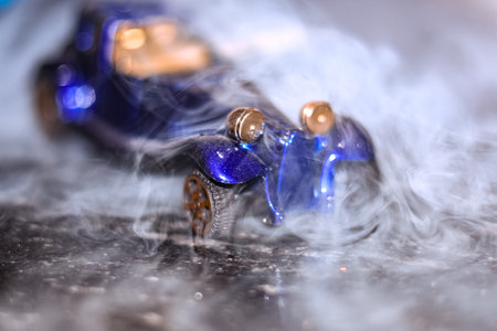 Close up shot of a blue toy car with smoke on the backgroundの写真素材