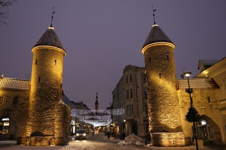 Tallinn, Estonia - January 7 2019 : view of old town gates with castle wall, towers and a Town Hall in winter at blue hour. Europe tourist attraction.のeditorial素材