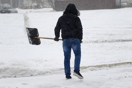 cleaning snow with shovel in winter dayの写真素材