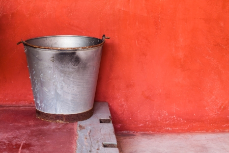 Small aluminum tank on step against red grunge wallの写真素材