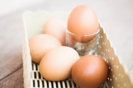 Chicken eggs in a basket on wooden table