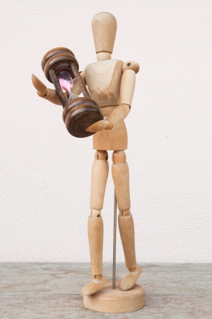 Wood mannequin and hourglass to represent time caringの写真素材