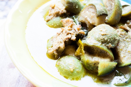 A bowl of spicy green curry with chicken and eggplantの写真素材
