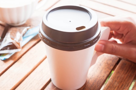 Hot coffee in paper cup serving on wood tableの写真素材