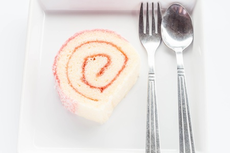 Strawberry jam lamington roll cake with spoon and fork, stock photo