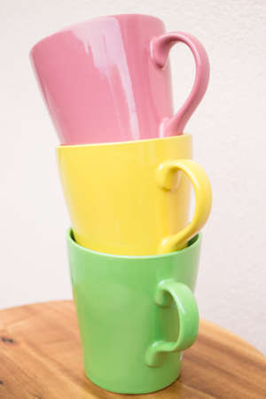 Sweet color mug cups on wooden table, stock photo