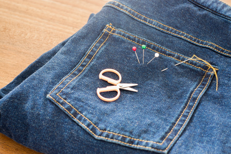 Needle with a thread through the jeanの写真素材