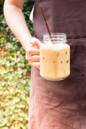 Barista serving iced coffee in the garden with vintage filter effect, stock photoの写真素材