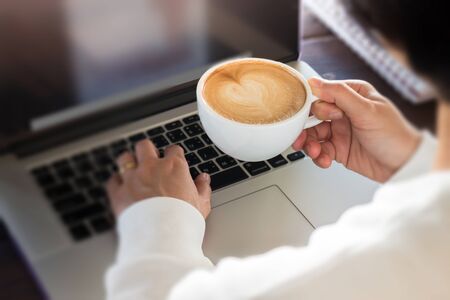 Hand on cup of coffee at work table, stock photoの写真素材