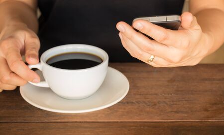 Hand on coffee cup and smartphone, stock photoの写真素材