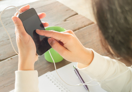 Woman wear headphones surfing the net by smart phone, stock photoの写真素材